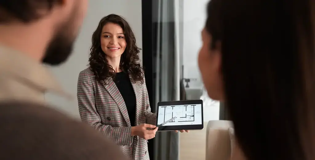 Vastgoedmakelaar toont plattegrond van appartement op tablet aan klanten tijdens consultatie